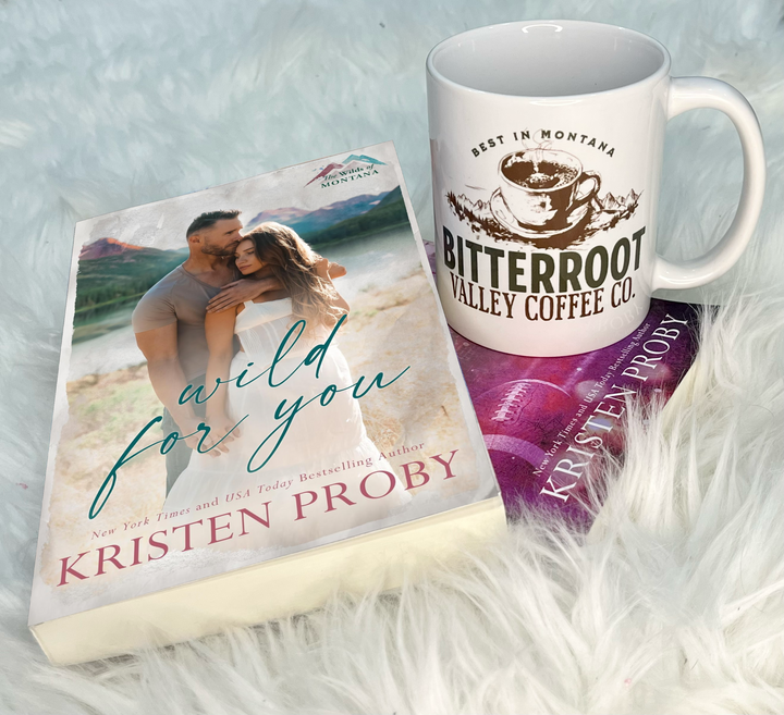 a book and a coffee mug sitting on top of a fluffy white blanket