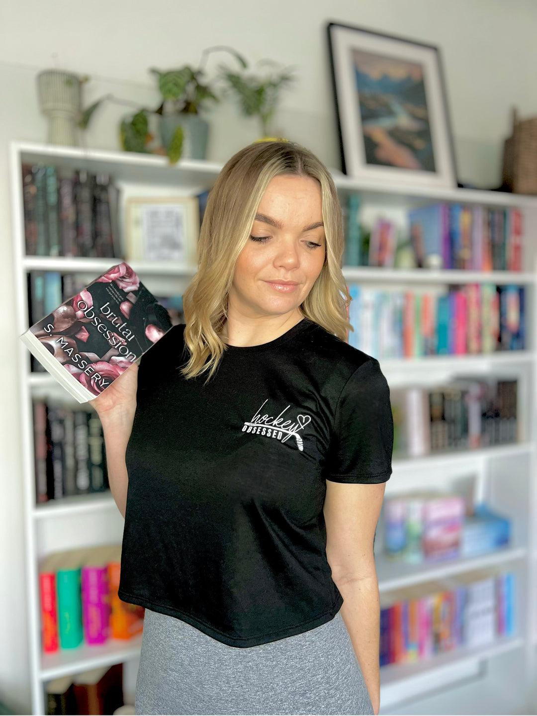 a woman holding a book in front of a bookshelf
