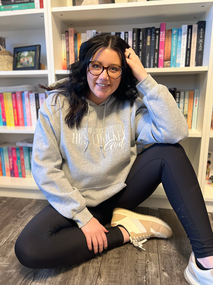 a woman sitting on the floor in front of a bookshelf