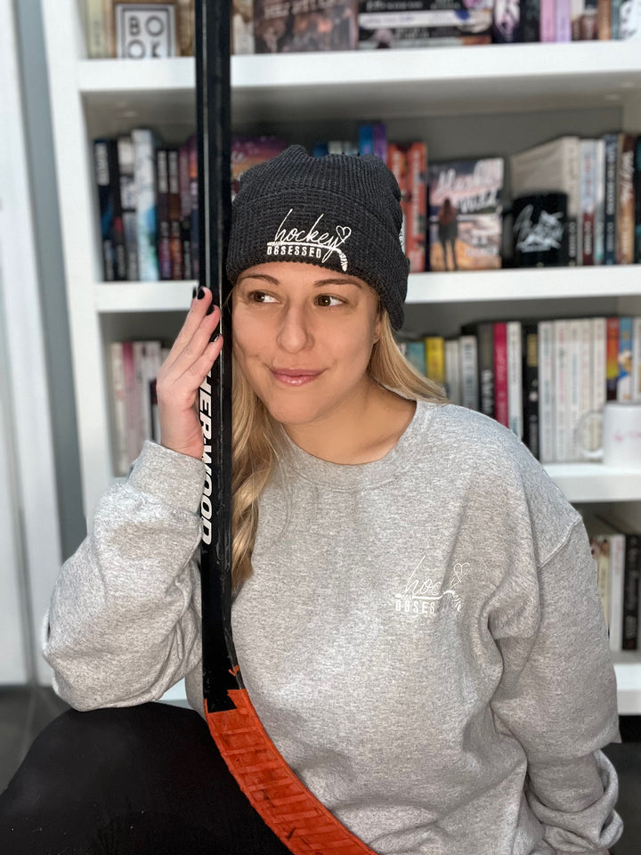 a woman sitting in front of a book shelf holding a baseball bat