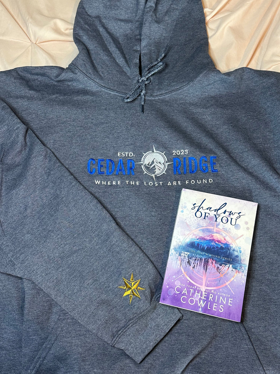 a book and sweatshirt laying on top of a bed