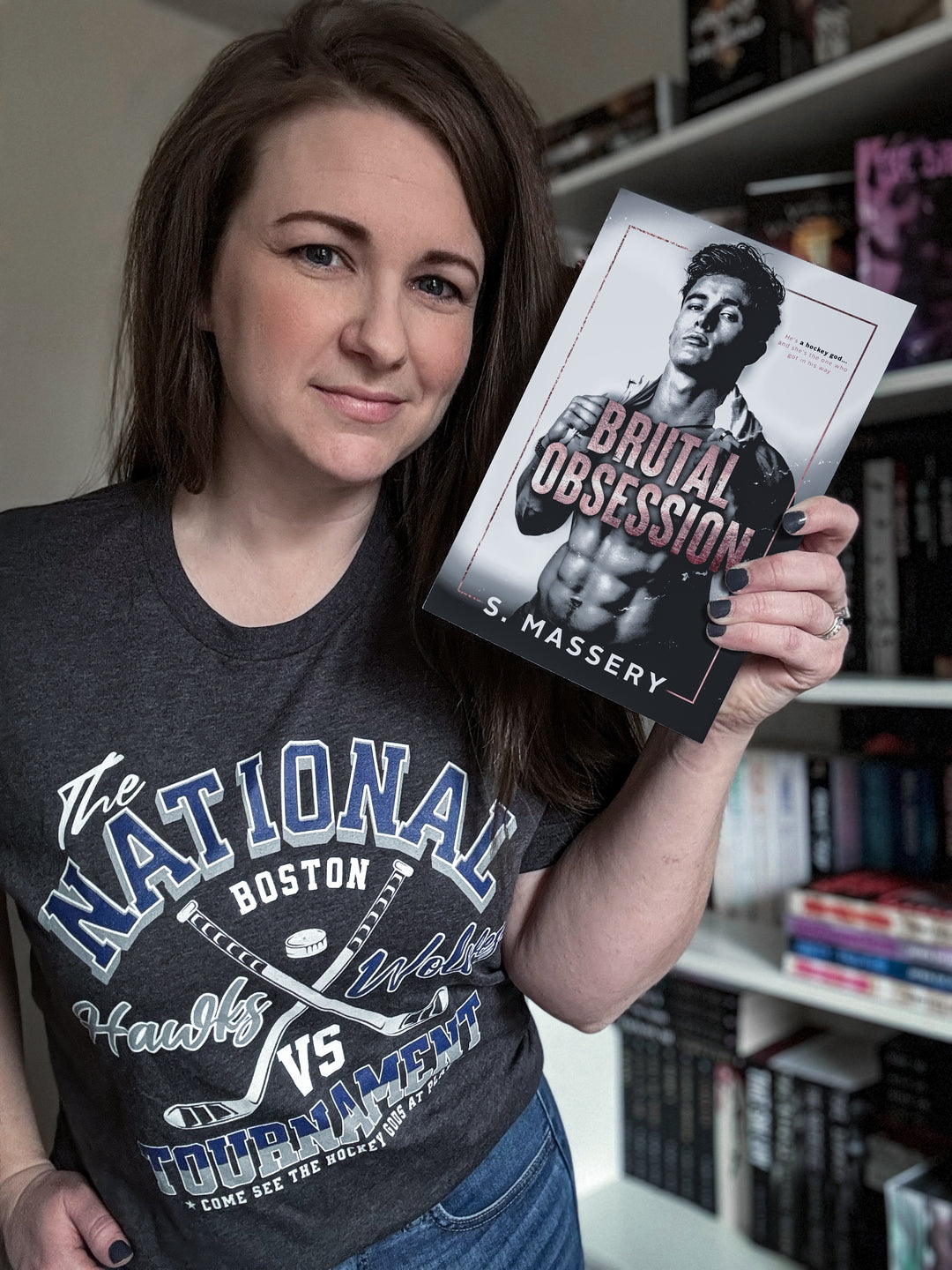a woman holding up a book in front of a bookshelf