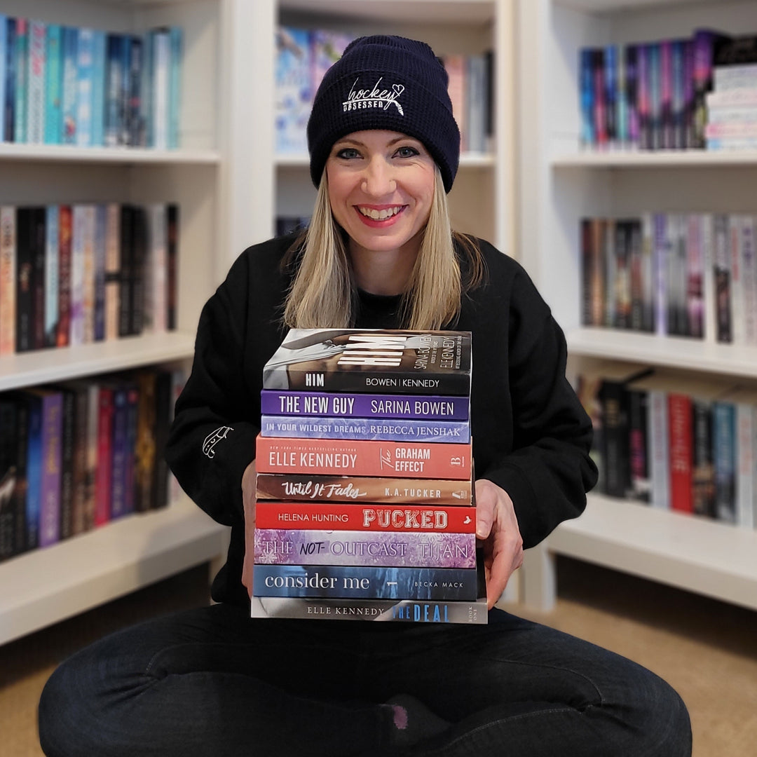 a woman sitting on the floor holding a stack of books