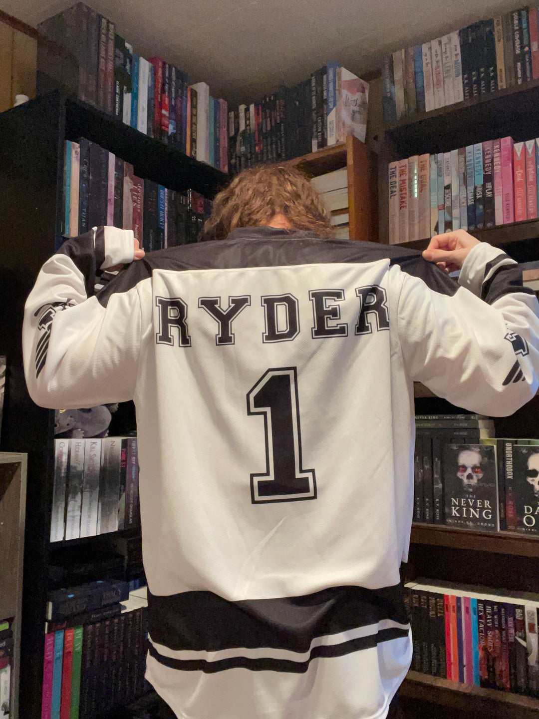 a person holding a large bag in front of a bookshelf