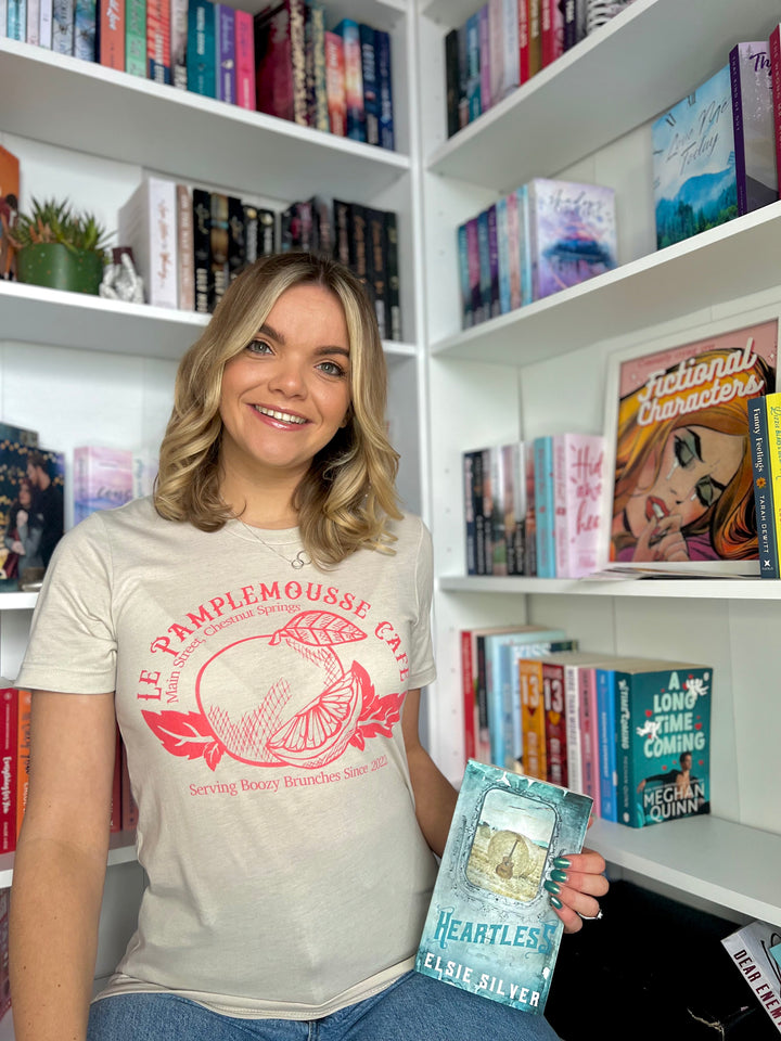 a woman holding a book in front of a bookshelf