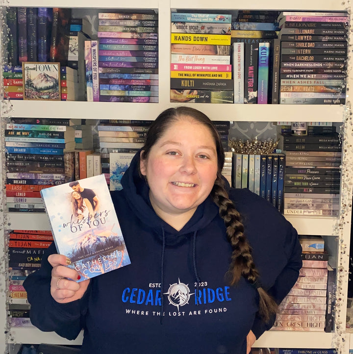 a woman holding a book in front of a bookshelf