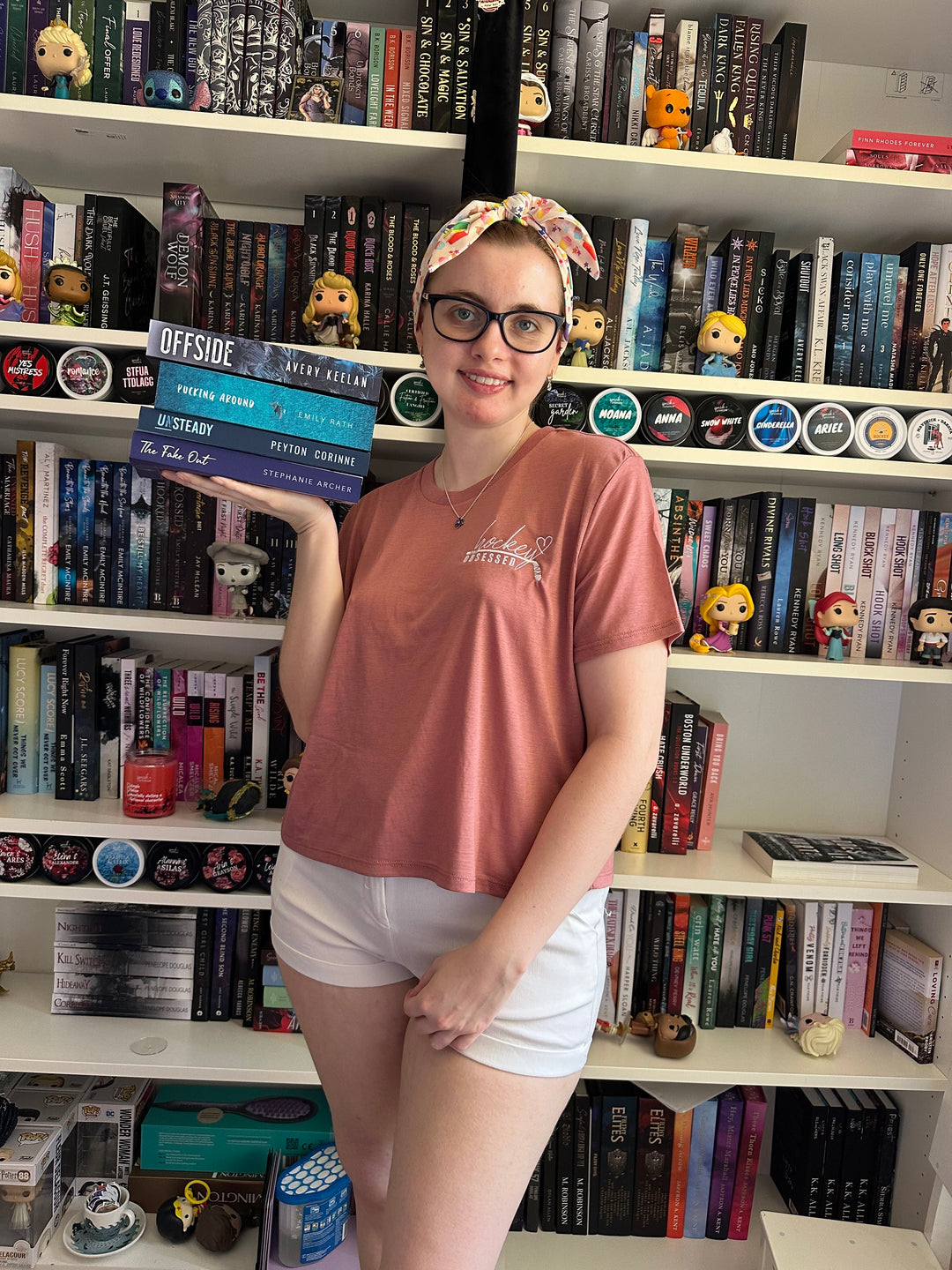 a woman standing in front of a book shelf filled with books