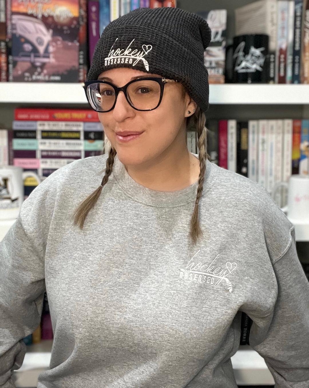 a woman wearing a hat and glasses in front of a bookshelf