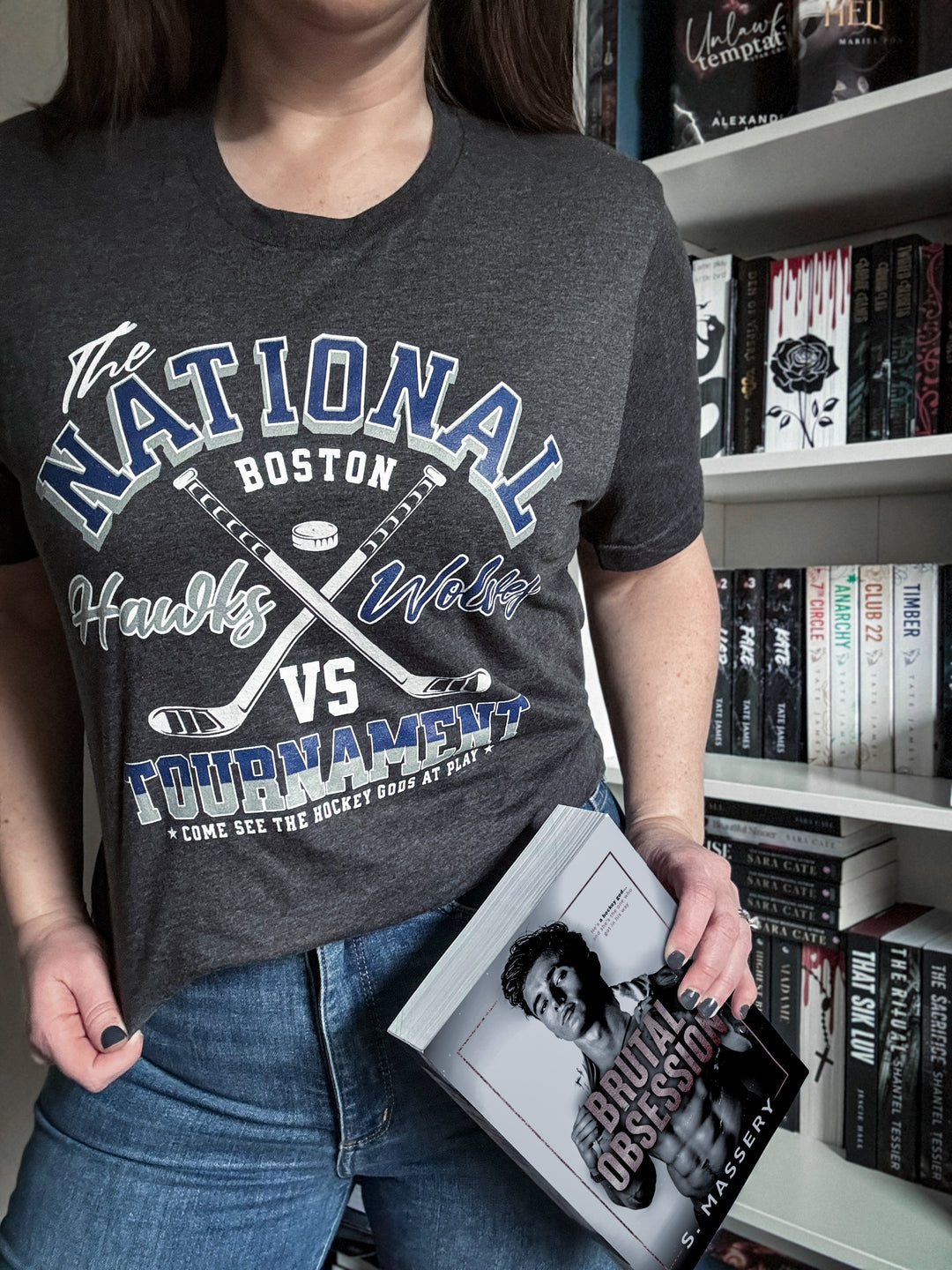 a woman holding a book in front of a bookshelf