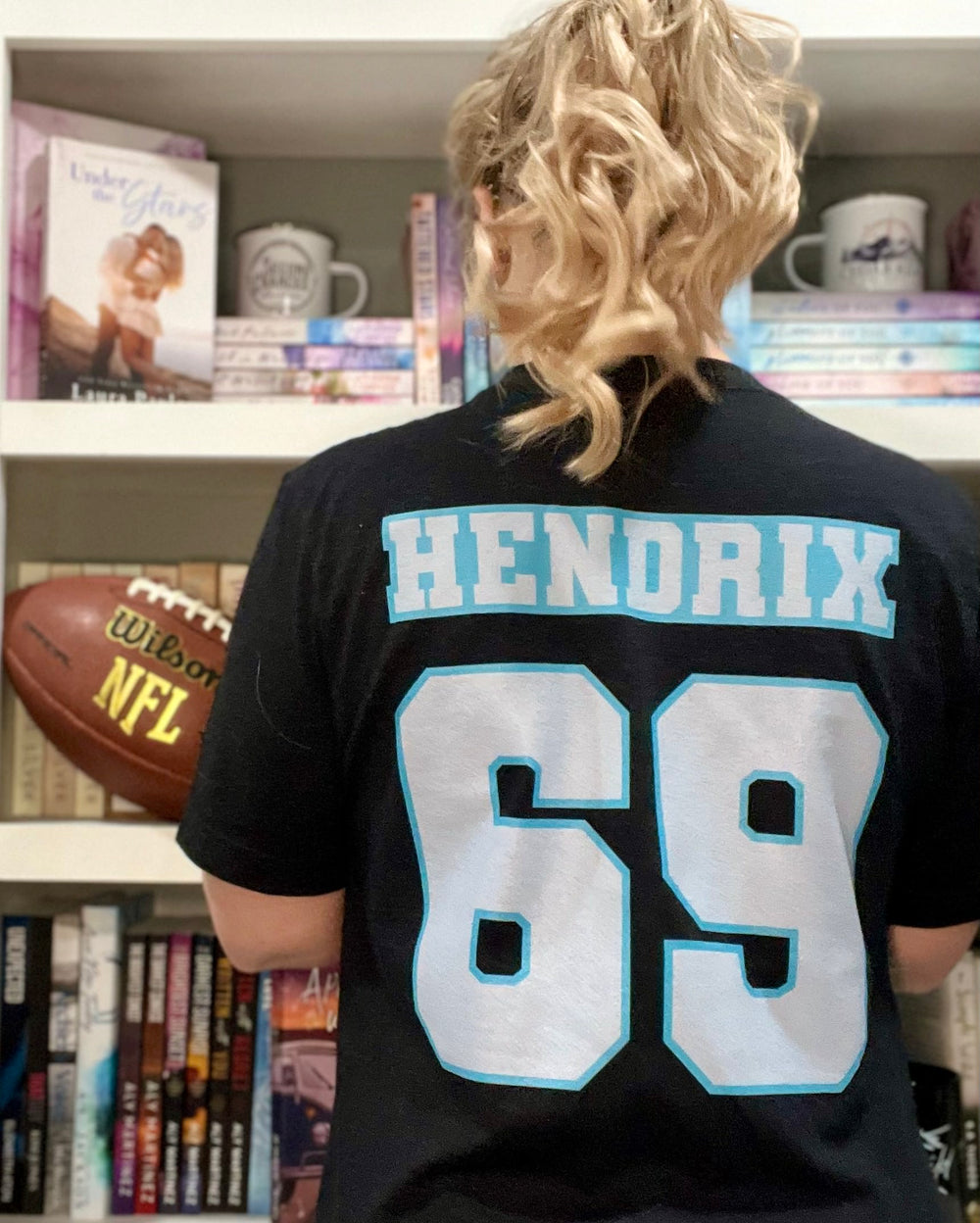 a person with a football in front of a book shelf