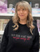 a woman standing in a store wearing a black sweatshirt that says keep your heart brave