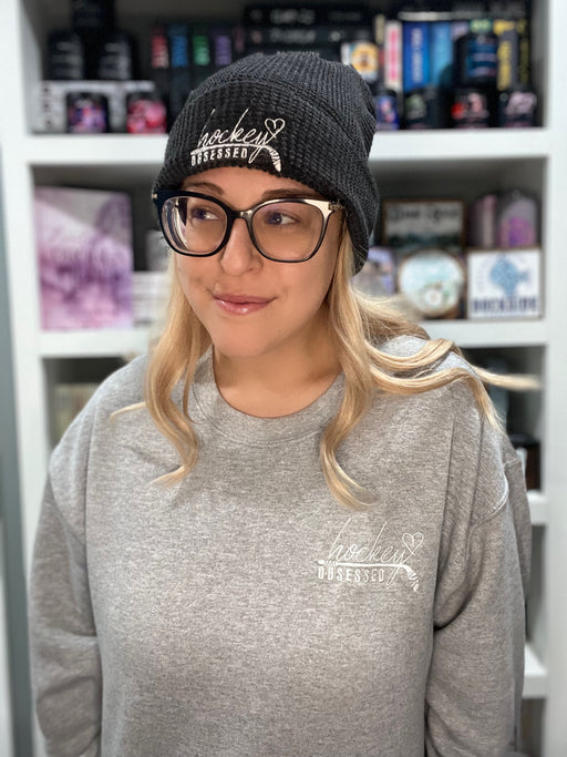 a woman wearing a hat and glasses standing in front of a book shelf