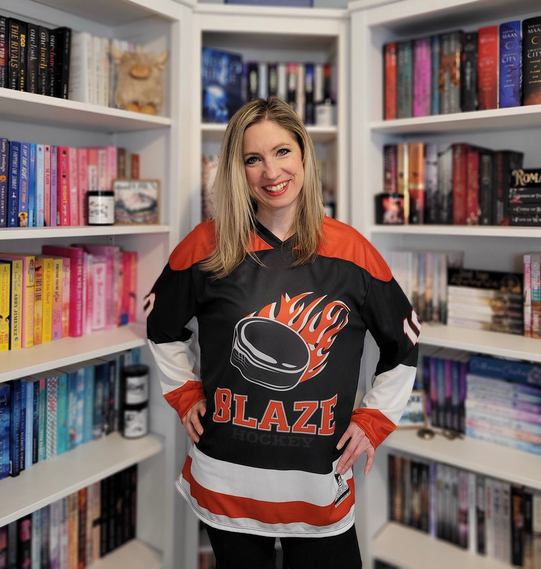 a woman standing in front of a book shelf holding a hockey jersey