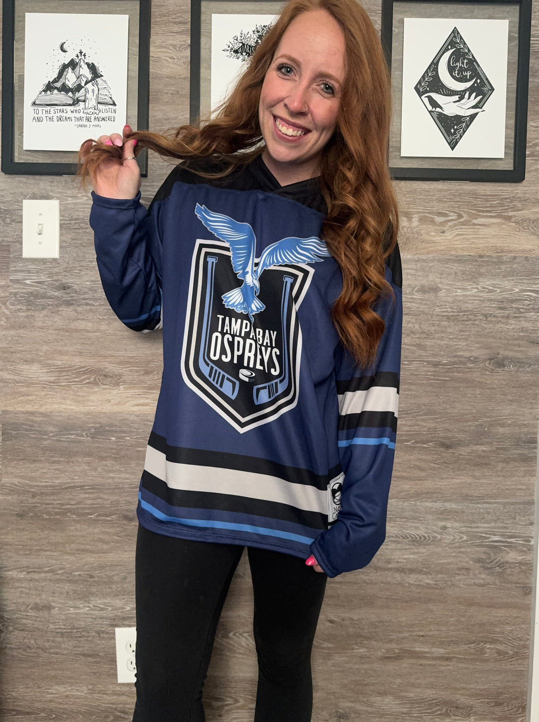 a woman standing in front of a wall wearing a hockey jersey