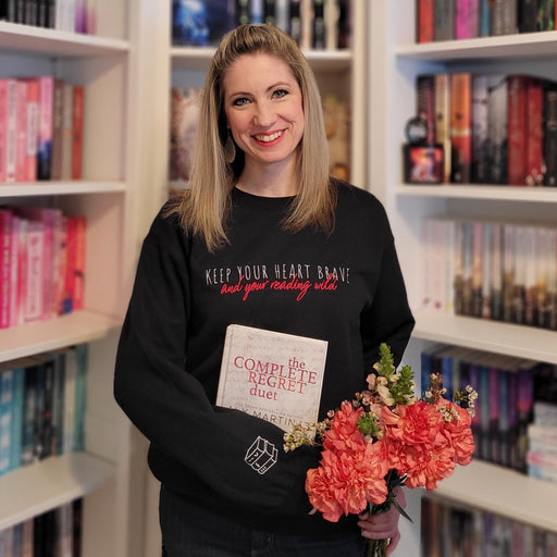 a woman standing in front of a book shelf holding a bouquet of flowers