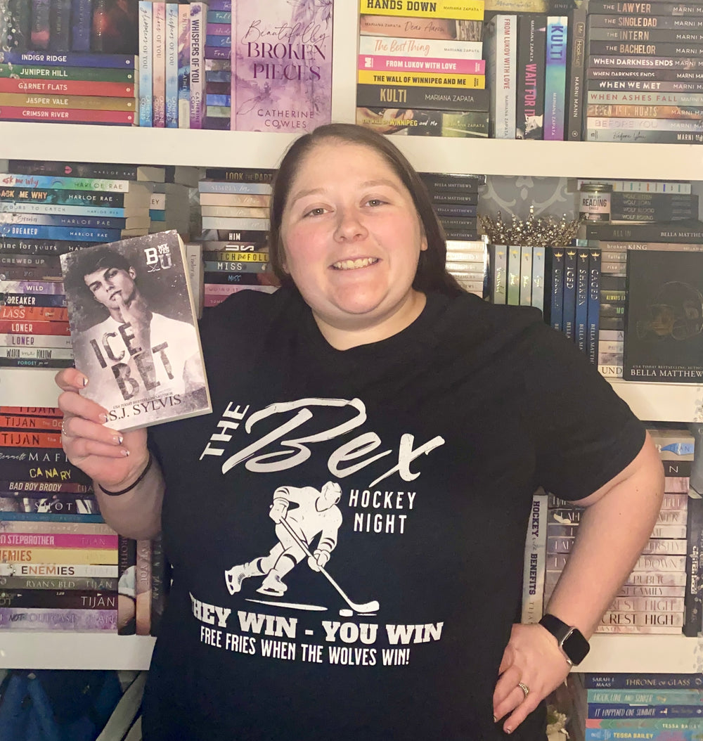 a woman holding up a book in front of a book shelf