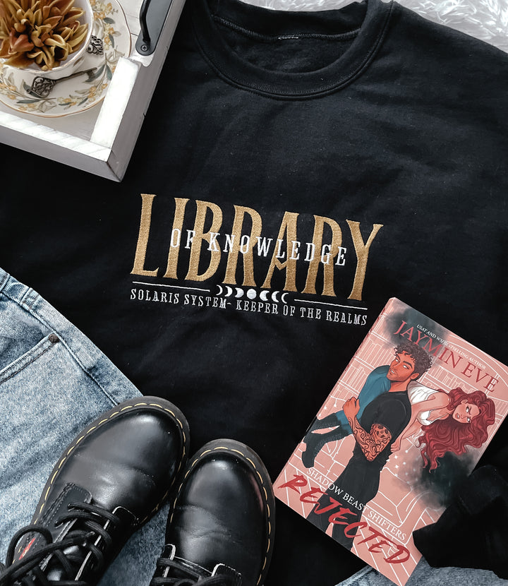 a black shirt with a picture of a woman and a book