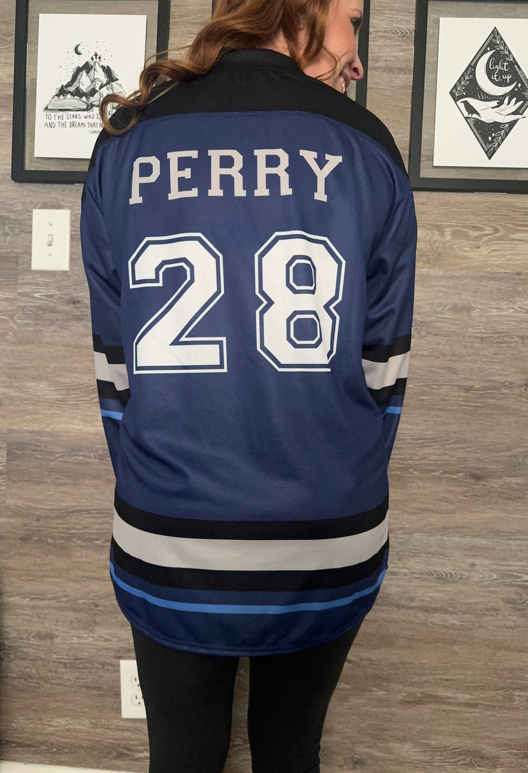 a woman wearing a hockey jersey standing in front of a wall