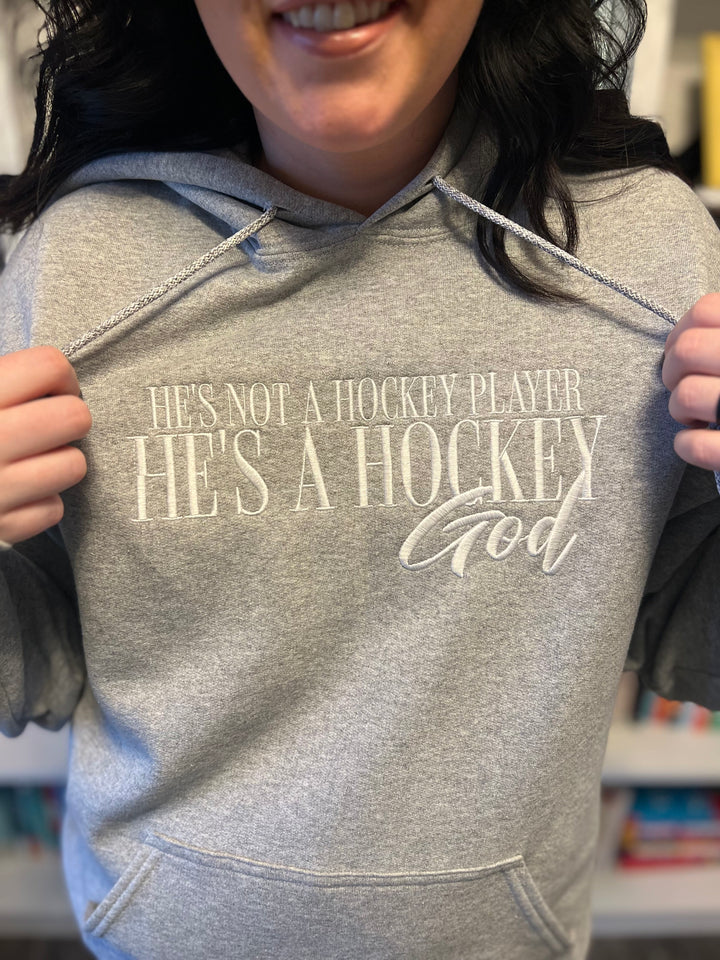 a woman is holding a hoodie that says he's not a hockey player