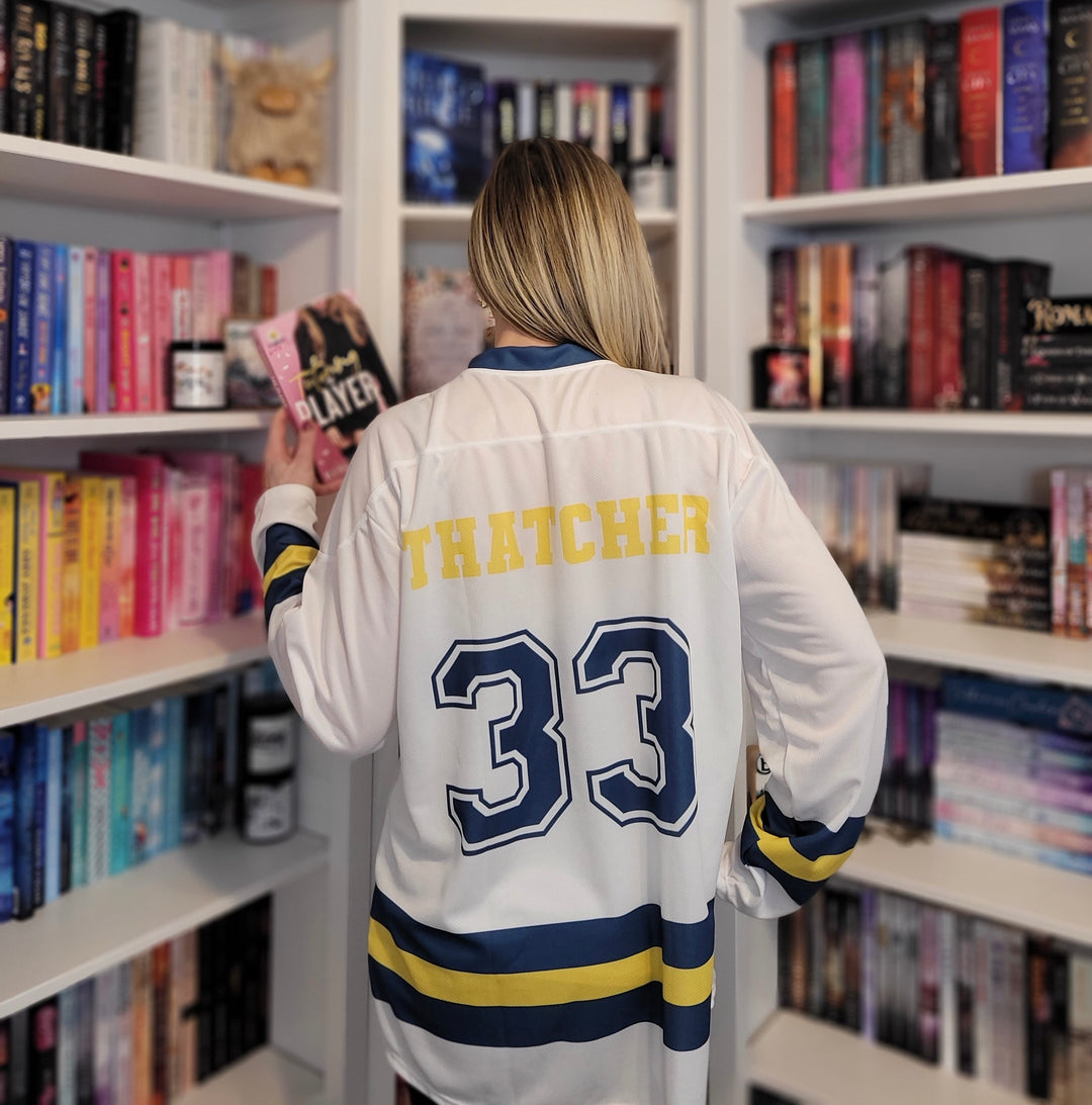 a woman standing in front of a book shelf holding a book