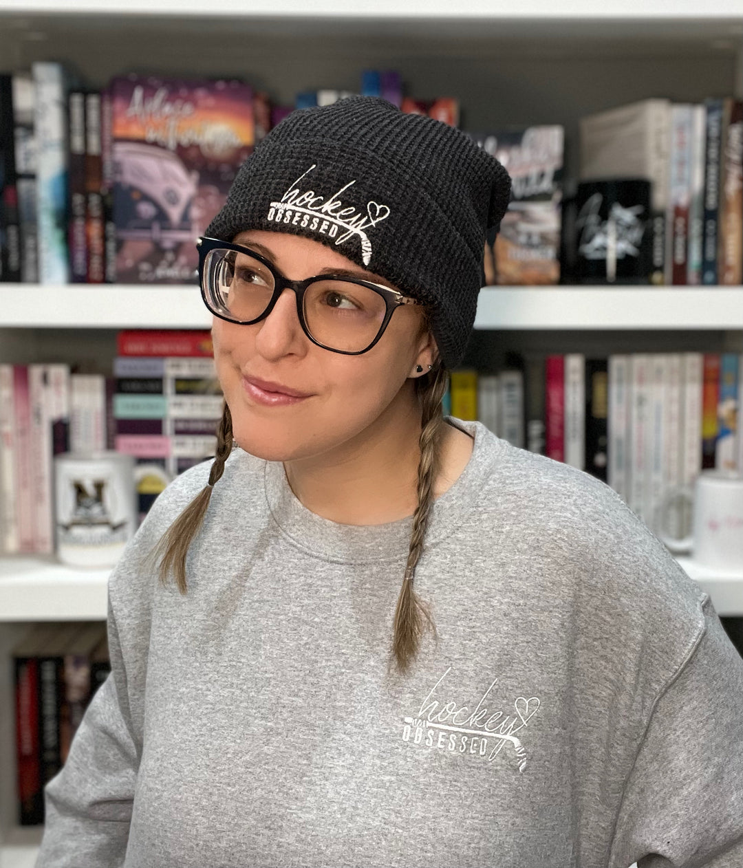 a woman wearing a hat and glasses in front of a bookshelf