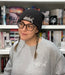 a woman wearing a hat and glasses in front of a bookshelf