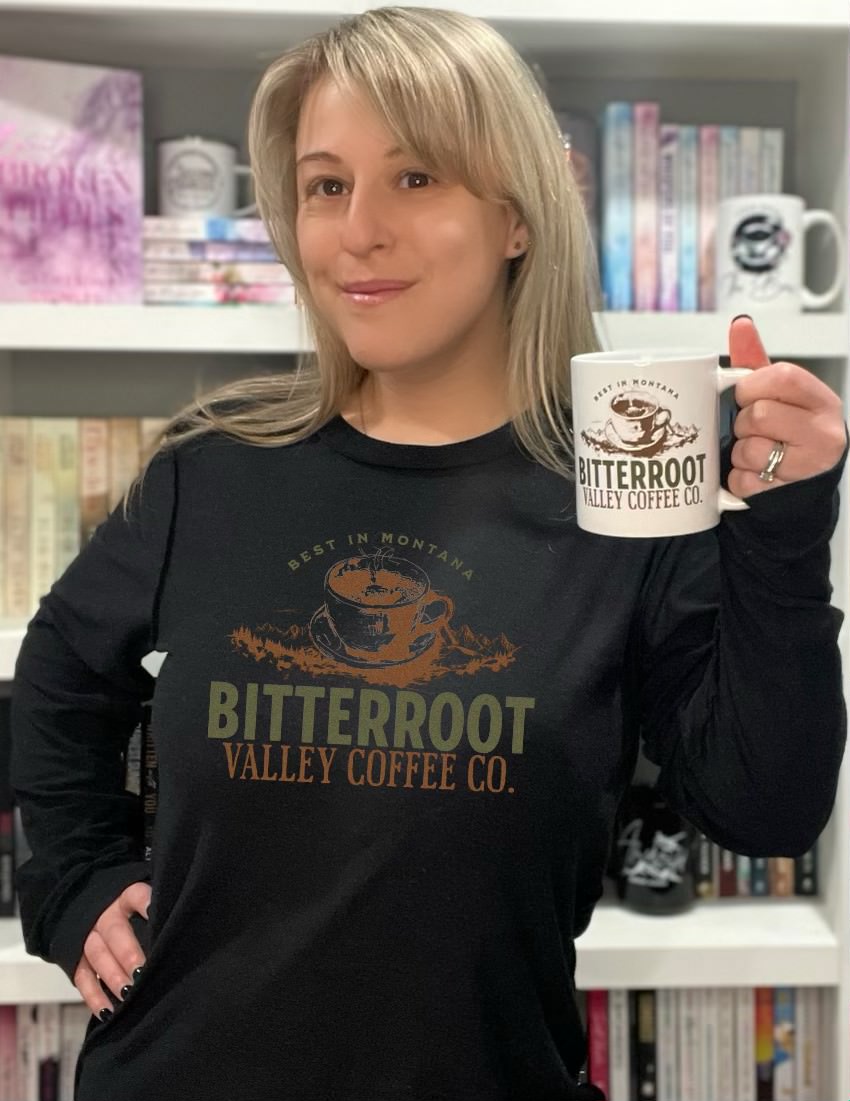 a woman holding a coffee mug in front of a bookshelf