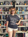 a woman wearing glasses standing in front of a wall of books
