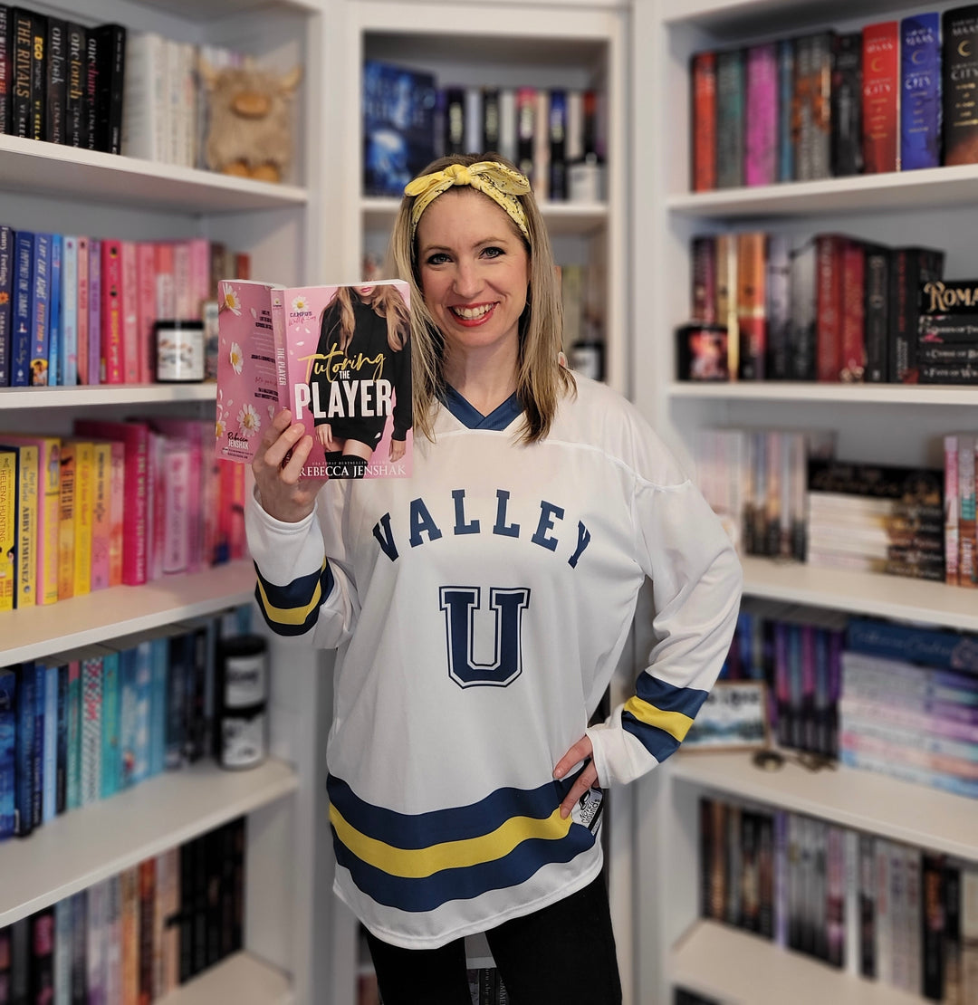 a woman holding up a book in front of a book shelf